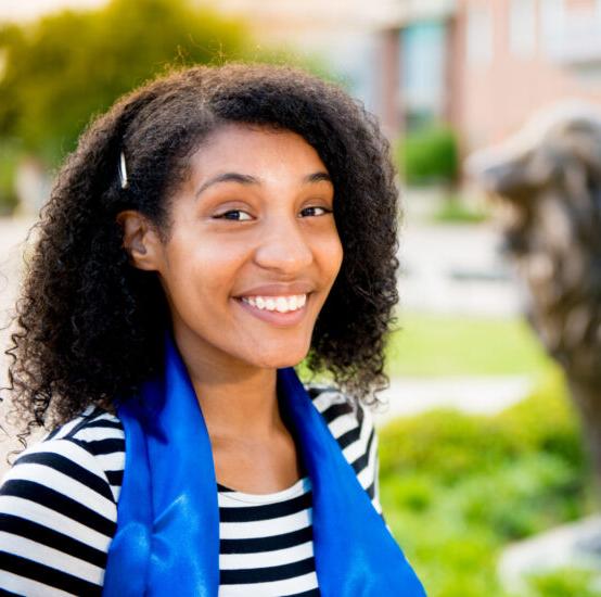 Young woman smiling while standing in front of university lion statue.